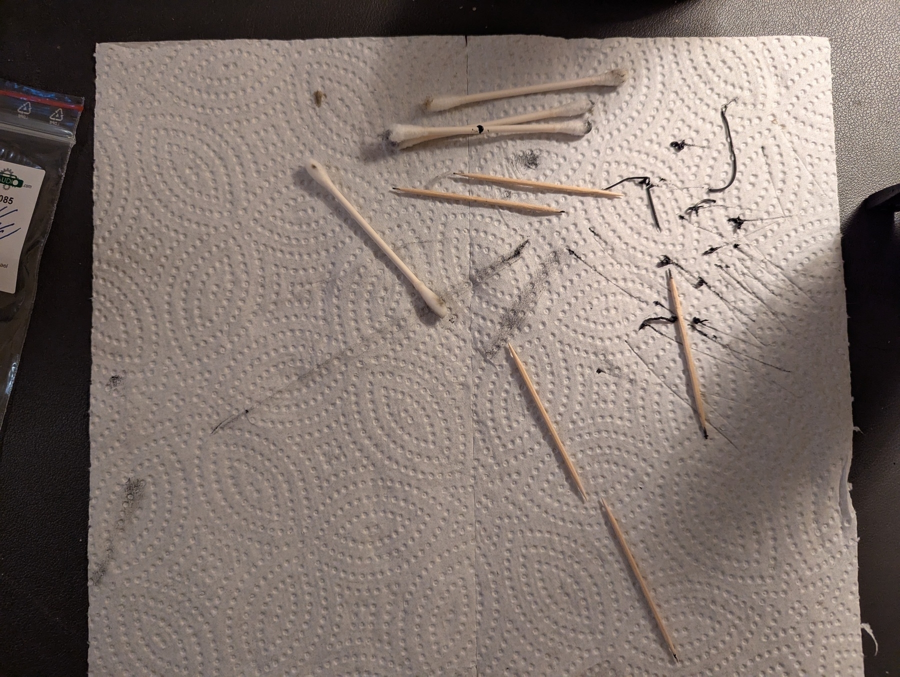 Paper towel with toothpicks, Q-Tips, and bits of melted and deteriorated tape player belt
